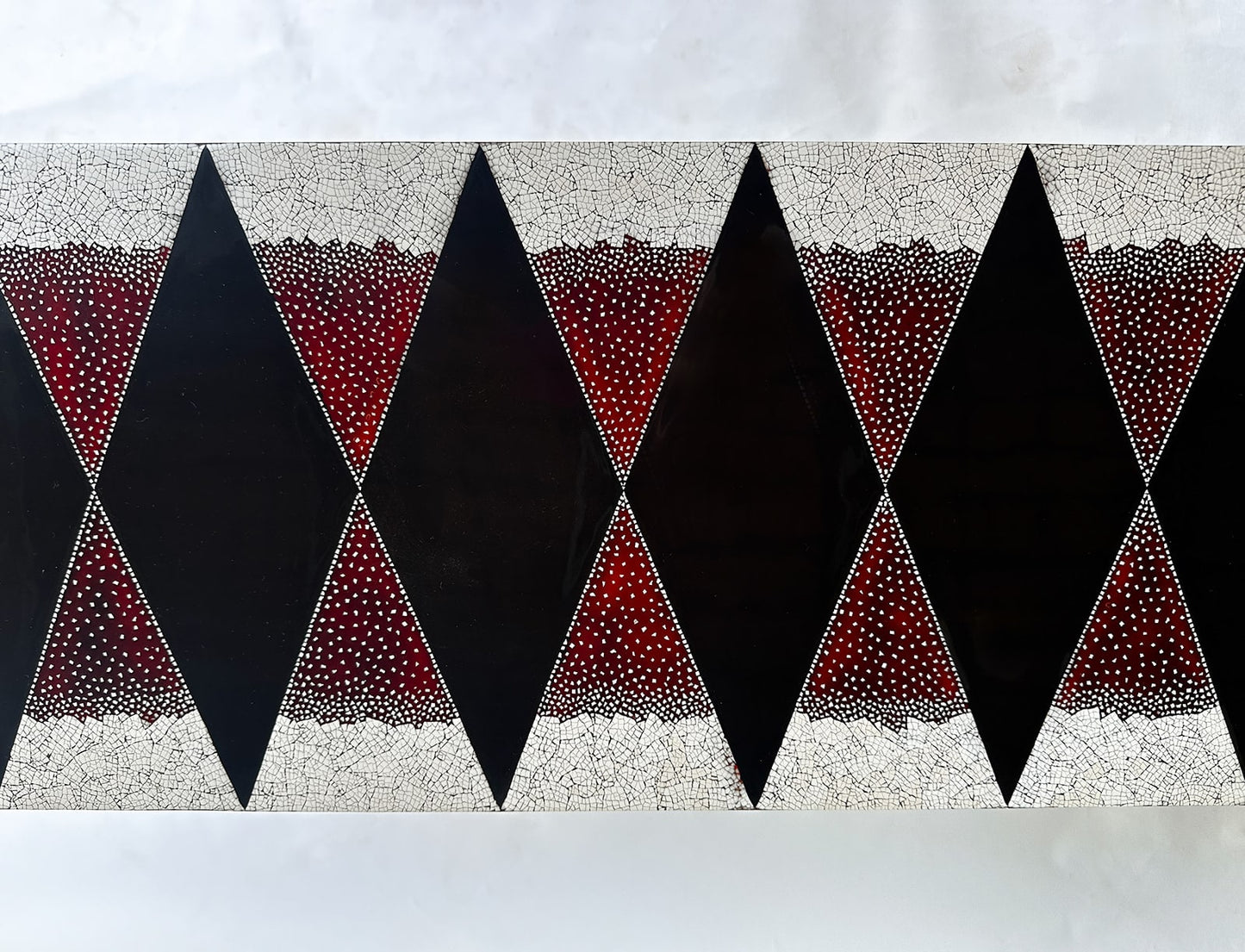 Detail of Stocker Studio lacquer console with black diamonds on red eggshell ground, framed by white eggshell mosaic bands