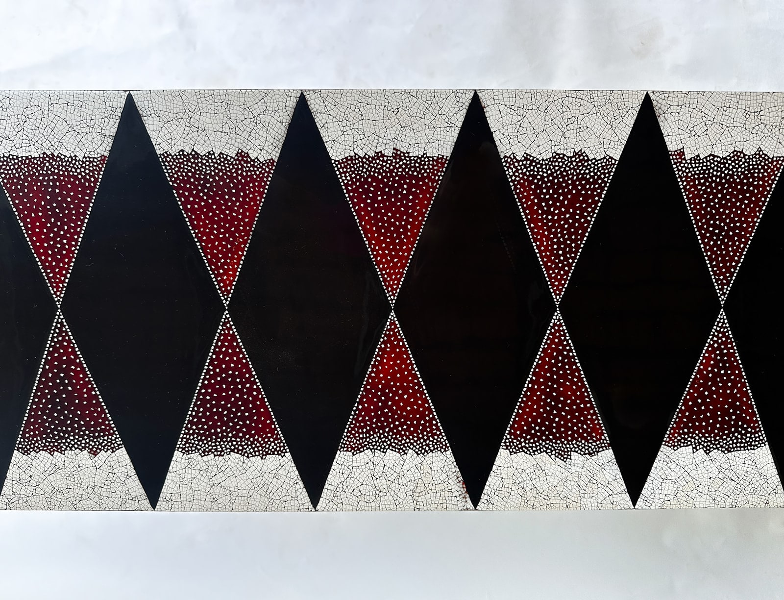 Detail of Stocker Studio lacquer console with black diamonds on red eggshell ground, framed by white eggshell mosaic bands